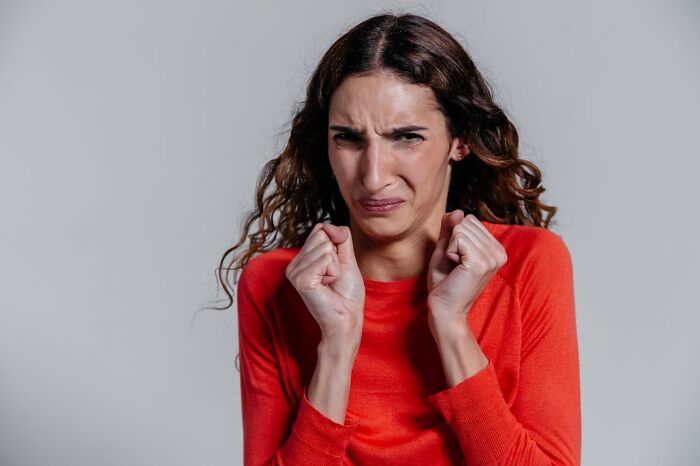 Mujer con expresión incómoda y manos cerca del rostro, mostrando reacción a peores cosas que escucharon accidentalmente.