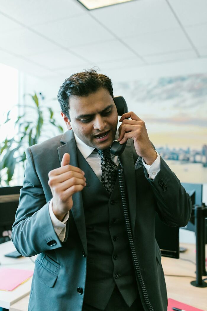 Hombre de negocios hablando por teléfono en oficina representando cosas que escucharon accidentalmente e inolvidables.
