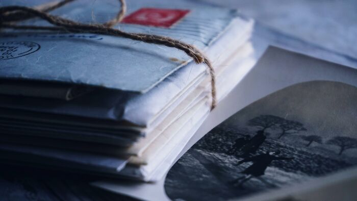 Cartas antiguas atadas con cuerda junto a una fotografía en blanco y negro, evocando misterios interesantes sin resolver.