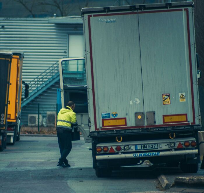Hombre revisando camión en zona industrial, representando secretos que las empresas ocultan a sus clientes diariamente.
