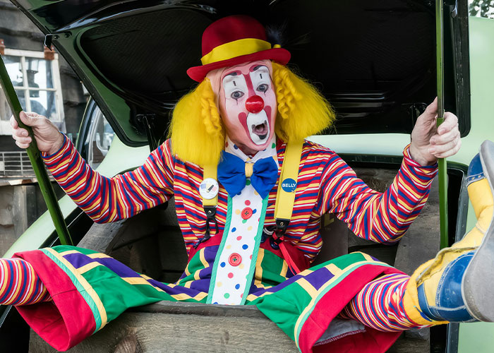 Payaso colorido sorprendido dentro de un maletero, ilustrando situaciones extrañas que investigadores privados han encontrado.
