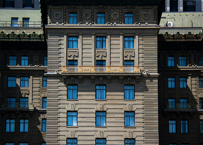 Fachada de edificio antiguo con múltiples ventanas, escenario de encuentros extraños de investigadores privados en su trabajo.