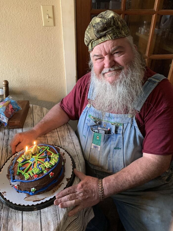 Hombre mayor sonriente con pastel de cumpleaños, imagen reconfortante para distraerse de los horrores actuales del mundo