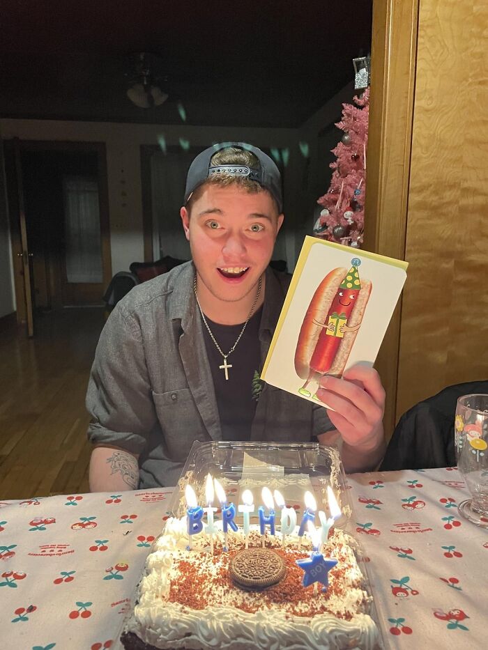 Joven celebrando cumpleaños con pastel y tarjeta, representando publicaciones reconfortantes para distraerte.
