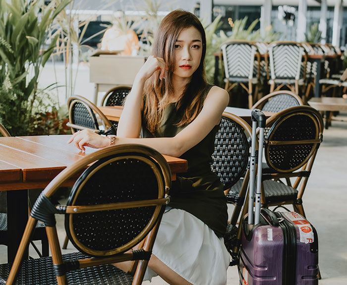 Mujer sentada en restaurante con maleta, escena que podría estar relacionada con citas terribles según camareros.
