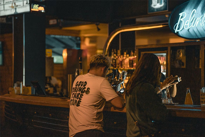 Hombre y mujer en bar oscuro, escena que refleja momentos típicos de citas terribles según camareros que las presenciaron.