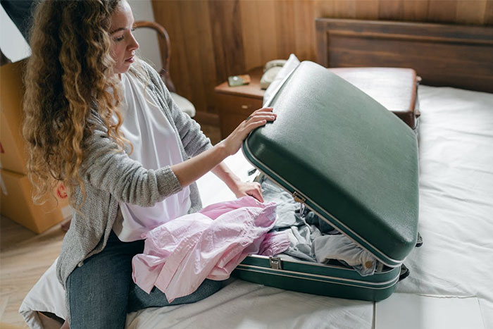 Mujer joven preparando maleta en habitación, imagen relacionada con citas terribles y experiencias de camareros.