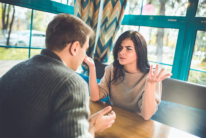 Pareja discutiendo en una cita incómoda en restaurante, ilustrando citas terribles según relatos de camareros.