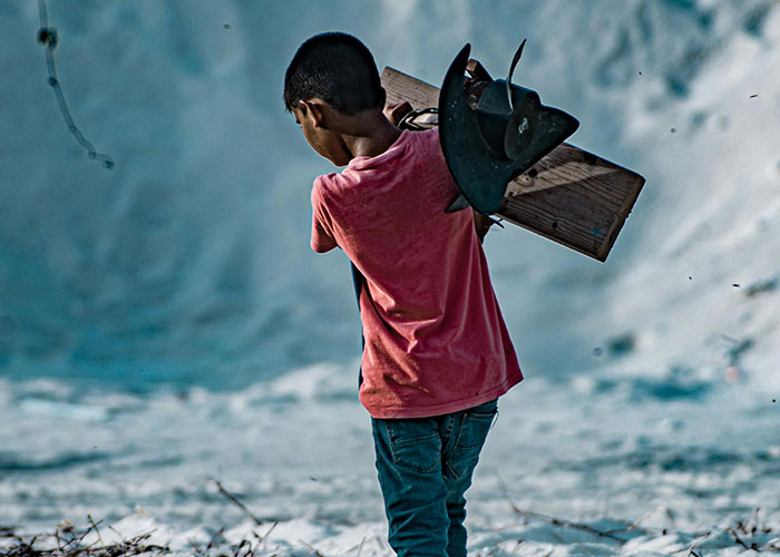 Niño con camiseta roja cargando madera en paisaje árido, concepto relacionado con datos inquietantes para insomnio.