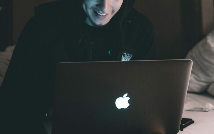 Persona sonriendo mientras usa una laptop Apple, representando experiencias intensas en Reddit que no son para débiles.