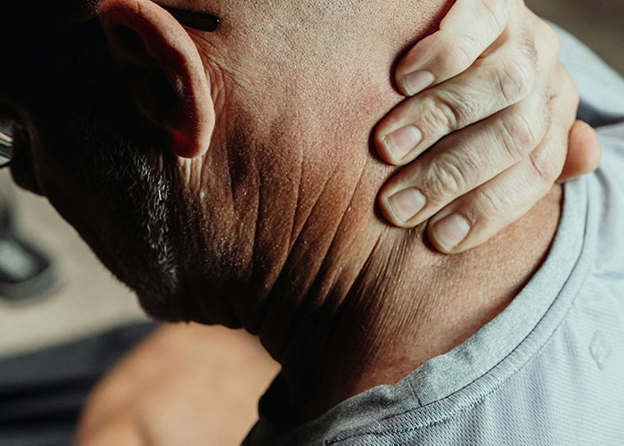 Hombre tocándose el cuello con expresión de incomodidad, pensando en datos inquietantes sobre insomnio y salud.