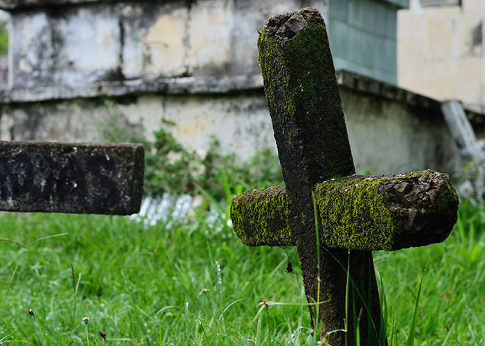 Cruz cubierta de musgo en cementerio antiguo con ambiente inquietante para reflexionar sobre insomnio y pensamientos oscuros