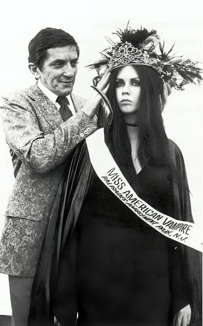 Hombre coronando a la ganadora del concurso Miss American Vampire en una foto antigua y con contexto histórico.