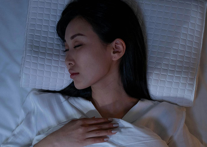 Mujer dormida en cama con luz tenue, reflejando insomnio y datos inquietantes para pensar por la noche.