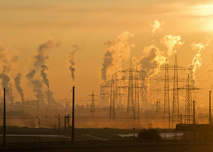 Fábricas y torres eléctricas con contaminación visible al atardecer, datos inquietantes para reflexionar en insomnio.