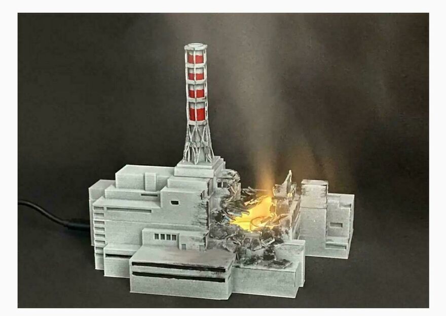 Humidificador del desastre de Chernobyl en miniatura con luz simulando el reactor dañado en un fondo oscuro.