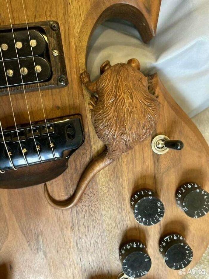 Guitarra eléctrica de madera con detalle creativo en forma de rata tallada mostrando buenas habilidades para ideas originales.