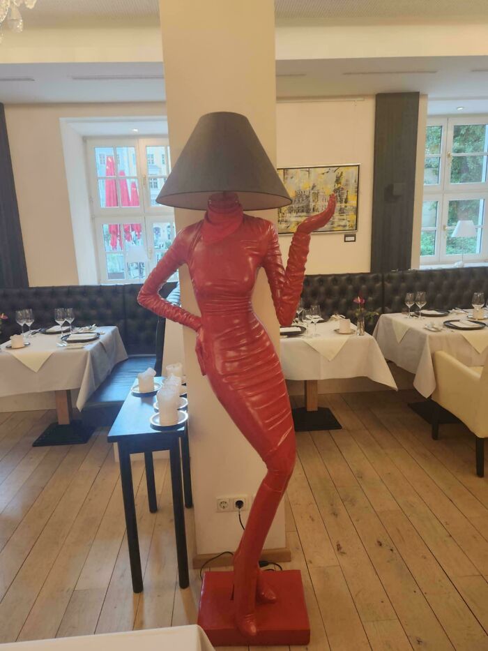 Figura estilizada con habilidades creativas representada como lámpara de pie con vestido rojo en restaurante elegante.