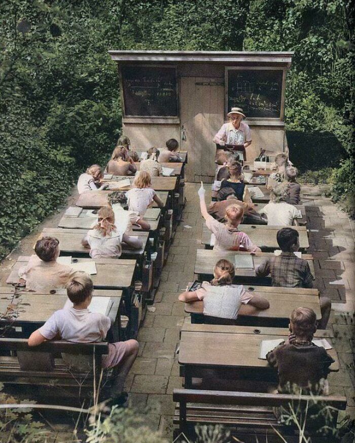 Clase al aire libre con niños en pupitres antiguos, representando datos e historias interesantes del mundo.