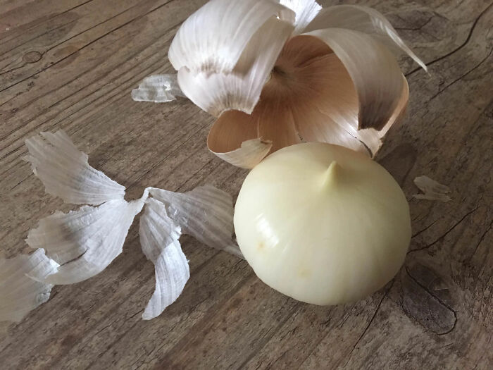 Cebolla blanca pelada sobre superficie de madera, ejemplo visual de datos e historias interesantes del mundo.