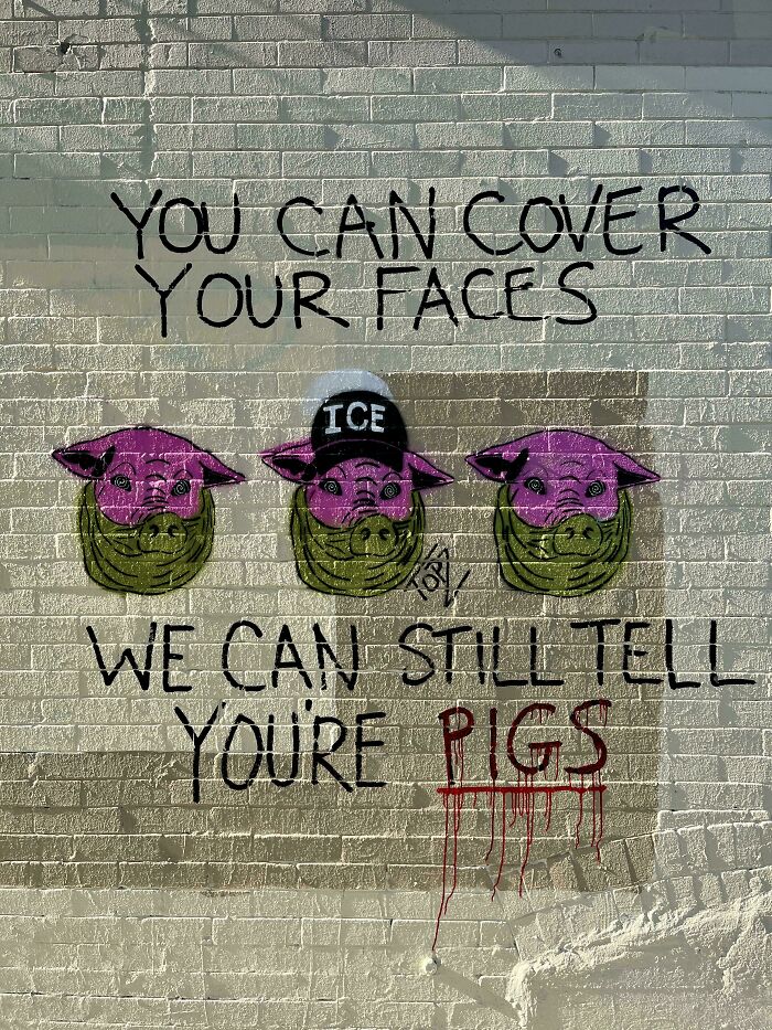 Grafiti en muro con mensaje sobre rostros cubiertos y cerdos, arte callejero simbólico en estilo chaotic good.