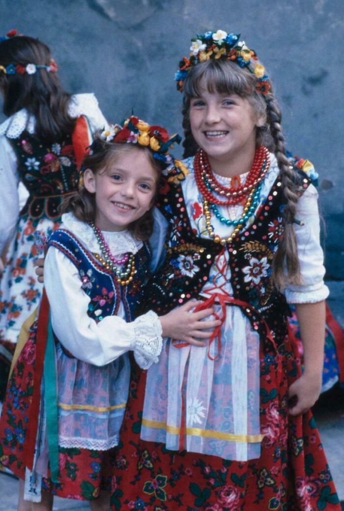 Niñas sonrientes con trajes tradicionales y flores, en una foto histórica fascinante que va más allá de los libros de texto.