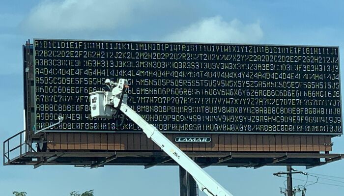 Cartel publicitario con error técnico que muestra caracteres y números ilegibles, ejemplo de fallos publicitarios divertidos.