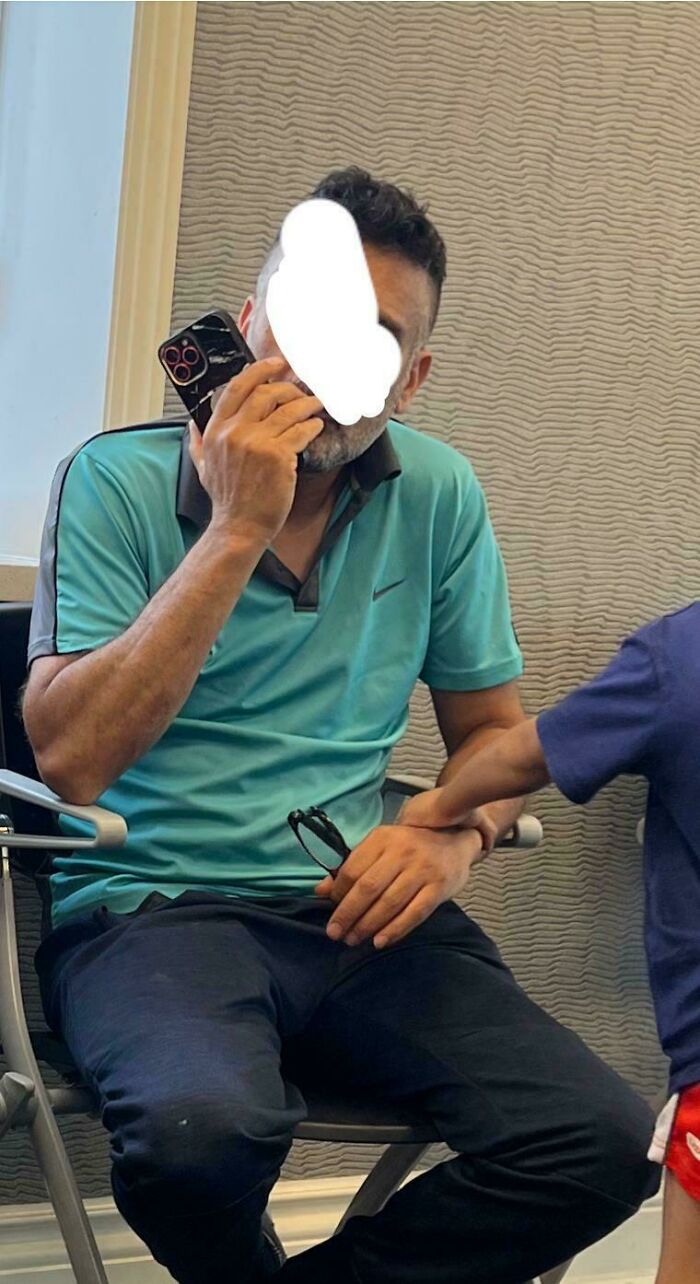 Hombre prepotente hablando por teléfono mientras un niño toma su mano en protesta en un interior moderno