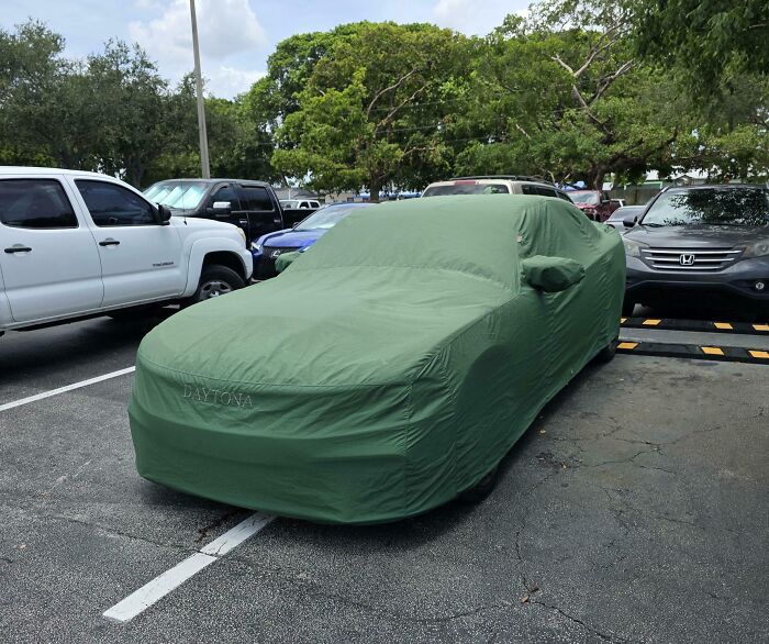 Coche cubierto en un estacionamiento rodeado de otros vehículos, mostrando personas prepotentes en internet.