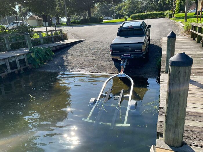 Camioneta con remolque parcialmente sumergida en el agua mostrando personas prepotentes actuando con derecho exagerado.