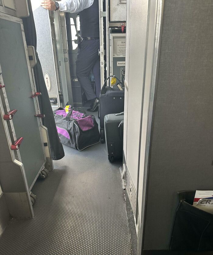 Persona prepotente bloqueando el pasillo de un avión con equipaje y causando incomodidad a otros pasajeros.