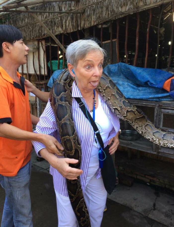 Mujer sorprendida con serpiente grande sobre los hombros en divertida foto de vacaciones de verano compartida.