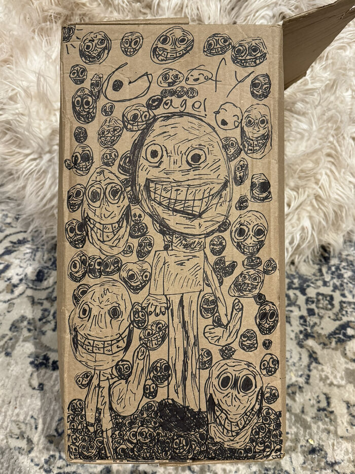 Dibujo aterrador con múltiples caras sonrientes y expresiones espeluznantes en una caja de cartón, imagen que provoca miedo.