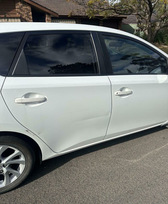 Raspón en la puerta de un coche blanco que muestra lo que es tener un hermano con actitud de derecho. Raspón en la puerta de un coche blanco que muestra lo que es tener un hermano con actitud de derecho.