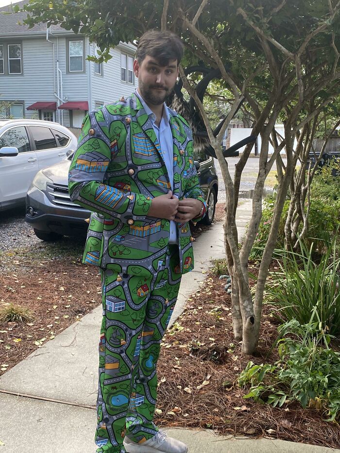 Hombre con traje colorido de diseño de calles y edificios, mostrando humor ingenioso y estilo único al aire libre.