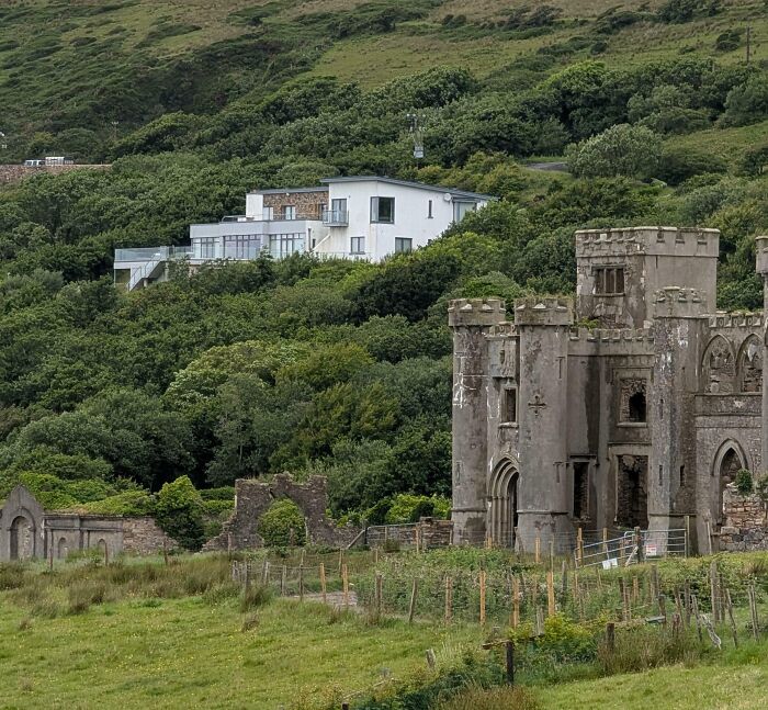 Casa moderna y castillo antiguo rodeados de naturaleza, mostrando la diversidad inesperada de la vida en el paisaje.