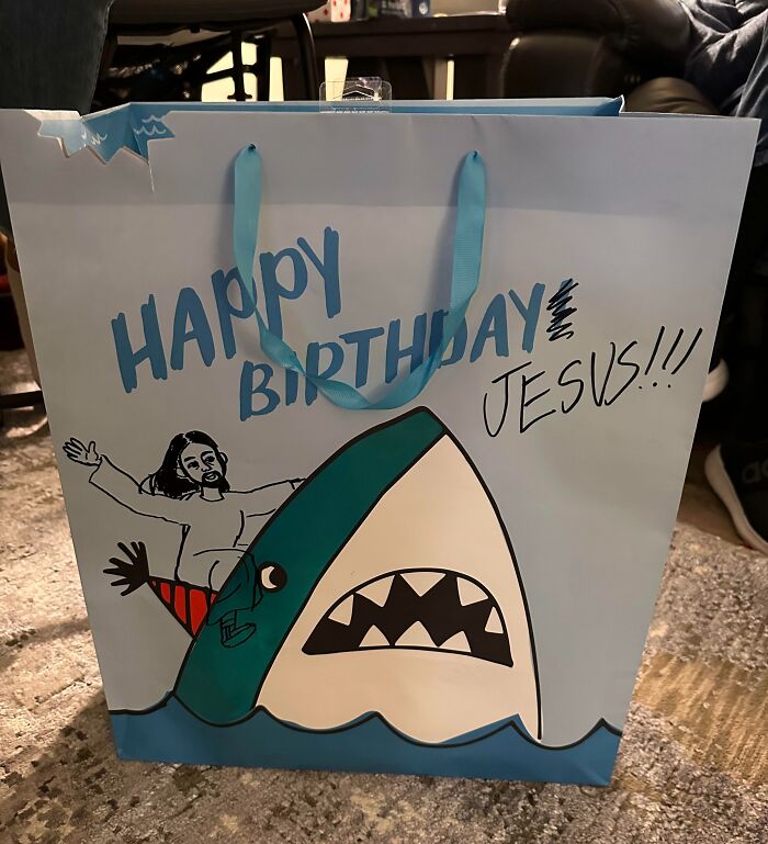 Bolsa de regalo con humor ingenioso que muestra un tiburón y Jesús celebrando un cumpleaños de forma divertida.