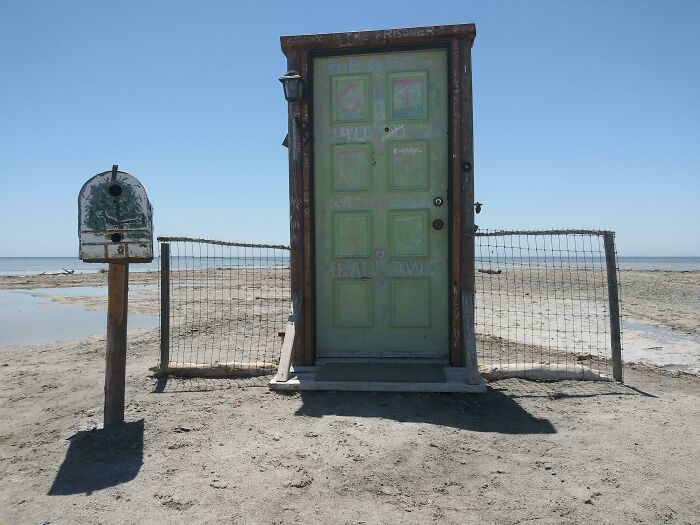 Puerta antigua y buzón oxidados en la playa, ejemplo de hallazgo inesperado en lugares costeros.