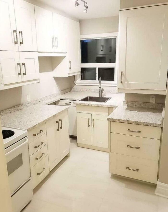 Cocina casera con diseño fallido, fregadero mal ubicado frente a ventana y encimeras mal ajustadas sin continuidad.