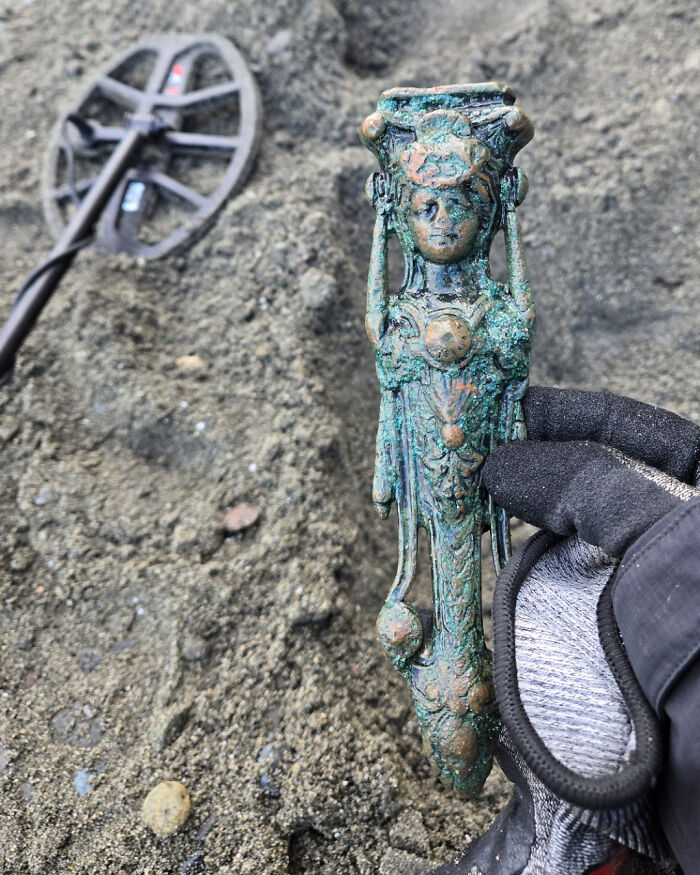 Estatua antigua encontrada en la playa usando detector de metales, ejemplo de hallazgo inesperado en la playa.