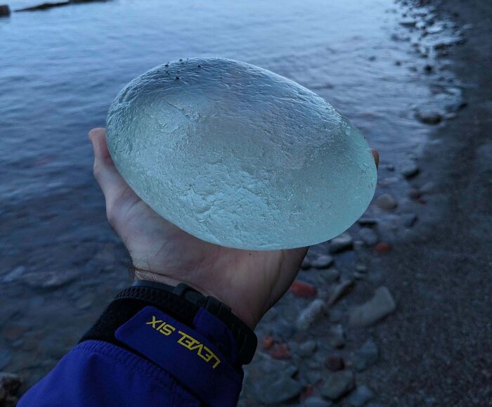 Mano sosteniendo objeto transparente inusual encontrado en la playa, muestra de hallazgos inesperados en la costa.
