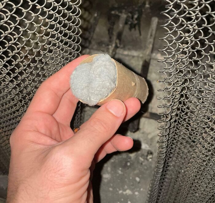 Mano sosteniendo un tubo de cartón relleno con lana para limpiar la chimenea, ejemplo de life hacks geniales usados.