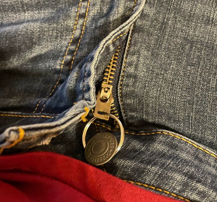Llave usada como tirador en cremallera de pantalón vaquero, mostrando truco ingenioso de life hacks prácticos.
