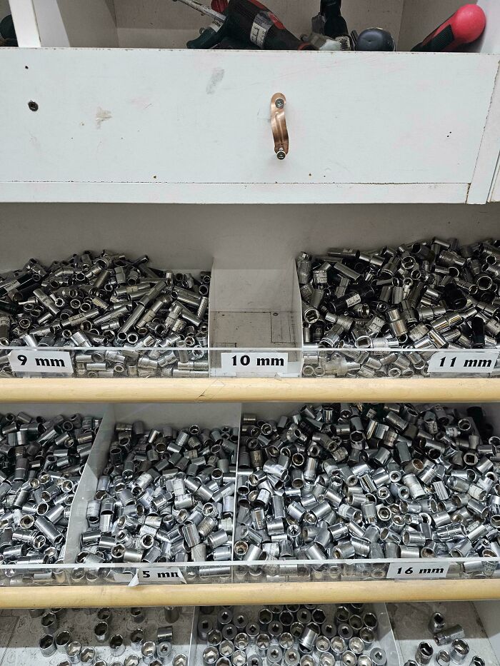 Estante con llaves de vaso organizadas por tamaño en taller mecánico, herramienta común para mecánicos de autos.