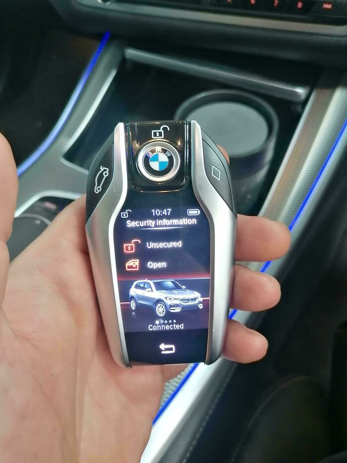 Llave digital BMW con pantalla que muestra estado de seguridad abierto, usada por mecánicos para evidenciar situaciones en autos.