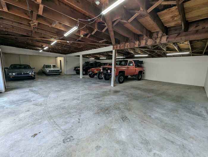 Garaje amplio con varios autos estacionados donde mecánicos toman fotos para documentar su trabajo en automóviles.