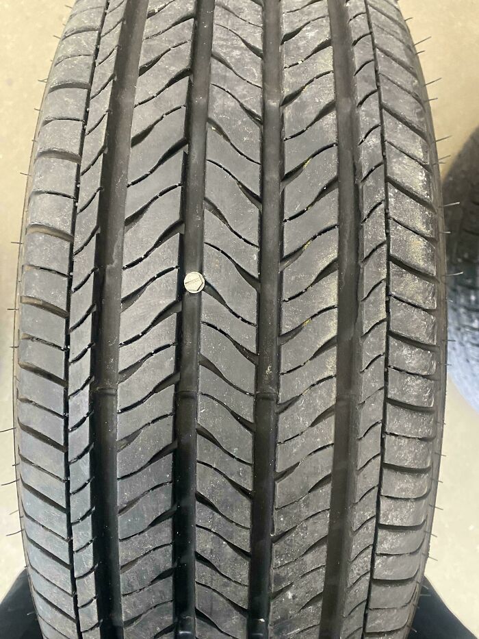 Neumático con un tornillo incrustado, imagen tomada por mecánico para mostrar daño real en reparación de autos.