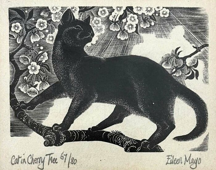 Gato negro dibujado en rama de árbol con flores, imagen adorable de gatos a través de la historia.