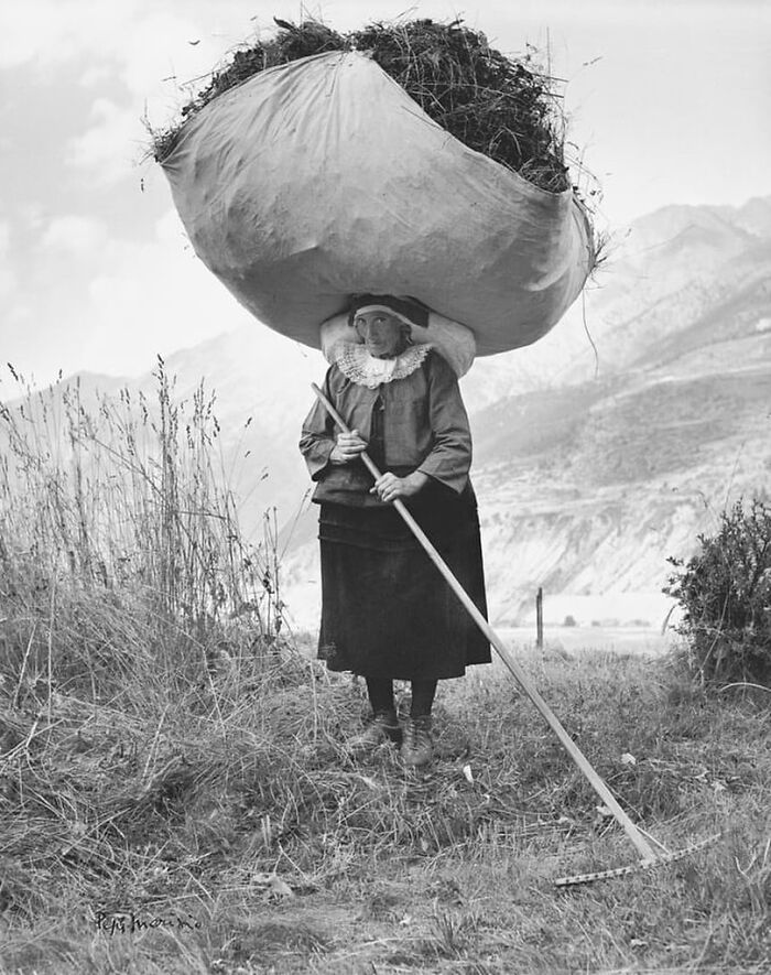 Mujer en foto antigua cargando gran carga en la cabeza, ilustrando contexto y detalles de fotos viejas históricas.