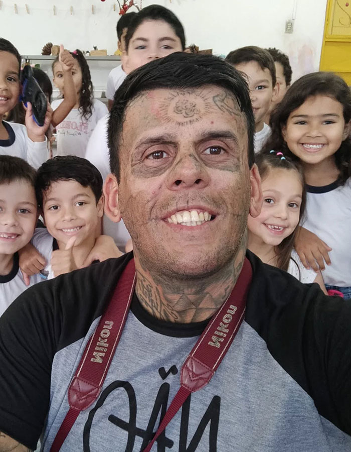 Hombre tatuado en 95% mostrando su nuevo aspecto impactante tras quitarse los tatuajes con láser, sonriente con niños.
